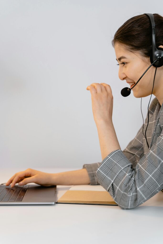 Smiling young woman in a call center working on a laptop with a headset.